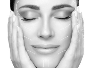 A black and white photo of a woman hodling her head in her hands with with white lines indicating how facial aesthetic surgery would change the face